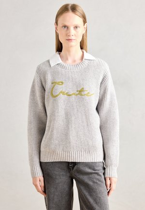 Gray ribbed sweater with a round neckline, featuring a gold cursive "Create" design on the front. Worn over a white collared shirt.