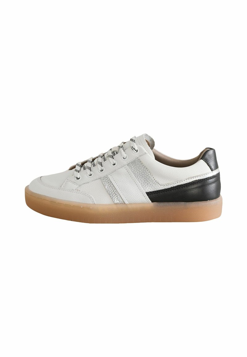 Sneaker en cuir blanc avec des accents noirs et gris, bout rond et côtés texturés. La semelle en caoutchouc beige et les lacets à motif complètent le design.