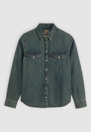 Camicia in denim blu con maniche lunghe, colletto a punta, due tasche sul petto, chiusura con bottoni sul davanti e bottoni bianchi a contrasto. Tessuto testurizzato.
