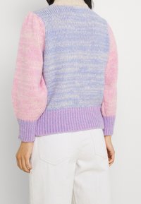 Pull en tricot avec un col haut, présentant un dégradé de bleu clair et de rose, des manches texturées et un ourlet côtelé.
