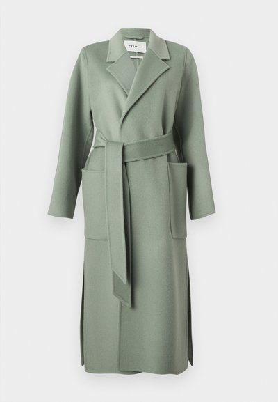 Μακρύ παλτό από μάλλινη ύφανση πράσινου φασκόμηλου με φαρδιές πέτες, ταιριαστή ζώνη, μεγάλες μπροστινές τσέπες και πλευρικές σχισμές.