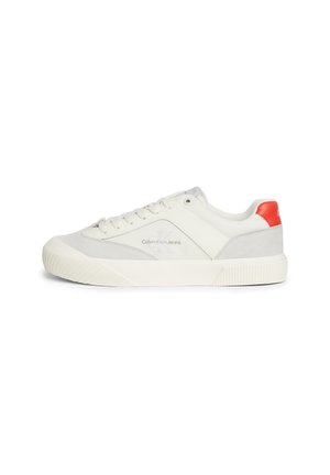 Sneakers Calvin Klein Jeans wyróżniają się białą cholewką z szarymi zamszowymi akcentami, czerwoną pętelką na pięcie oraz teksturowaną gumową podeszwą. Czysty, minimalistyczny design.