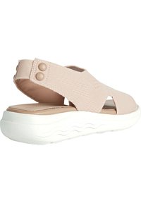 Infradito di tessuto rosa chiaro con una fascia elastica, punta aperta e suola bianca a onde. Presenta due bottoni decorativi sulla fascia.
