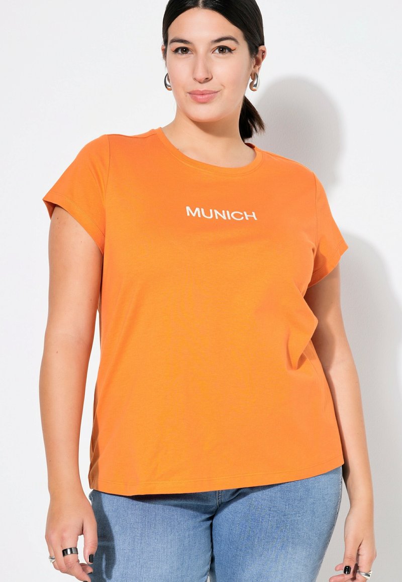Orange Kurzarm-T-Shirt mit weißem "MÜNCHEN"-Text auf der Vorderseite. Weicher Baumwollstoff, lässige Passform, runder Halsausschnitt und subtile Seitenschlitze.