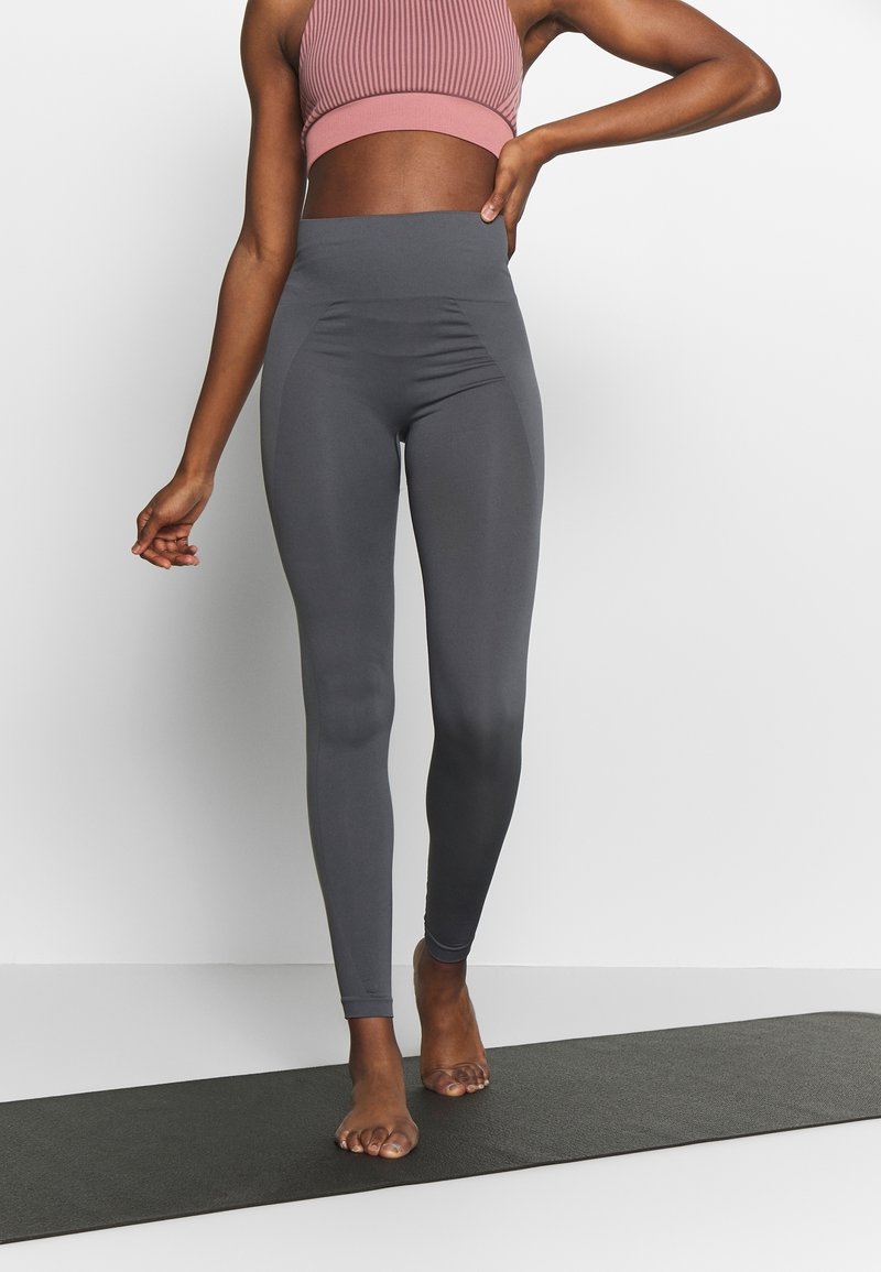 Hög midja, grå leggings gjorda av elastiskt material, med en slät yta och subtila sidpaneler. Designade för komfort och flexibilitet.