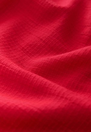 Textil rojo con una superficie texturizada que presenta un patrón de cuadrícula. La tela es suave y ligeramente reflectante, lo que resalta su color uniforme.