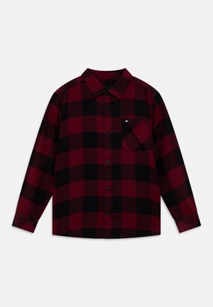 Camisa de manga larga con botones y patrón de cuadros rojo y negro, cuello, bolsillo delantero y botones negros sobre fondo liso.