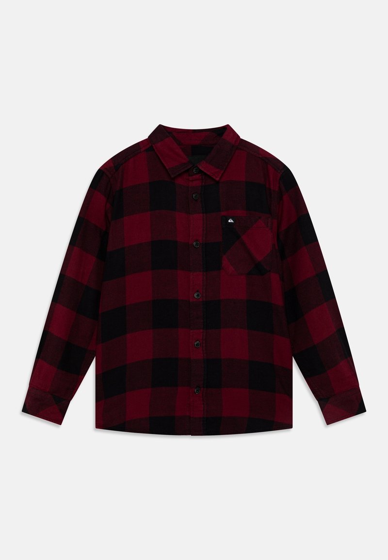 Chemise à manches longues boutonnée avec motif à carreaux rouge et noir, col, poche avant et boutons noirs sur fond uni.