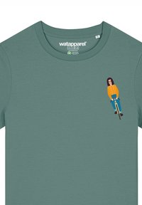 Groene katoenen t-shirt met een cartoonfiguur op een fiets, gekleed in een oranje trui en blauwe spijkerbroek, met zwarte schoenen en een bril.