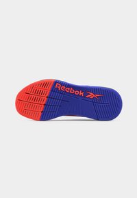 Podeszwa buta z niebiesko-czerwonym bieżnikiem, z podniesionymi liniami i logo "Reebok" w kolorze czerwonym na niebieskim tle pośrodku.
