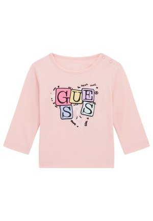 Pink long-sleeve shirt made of cotton featuring a colorful "GUESSS" graphic print with hearts and playful text accents. Snap button on shoulder.