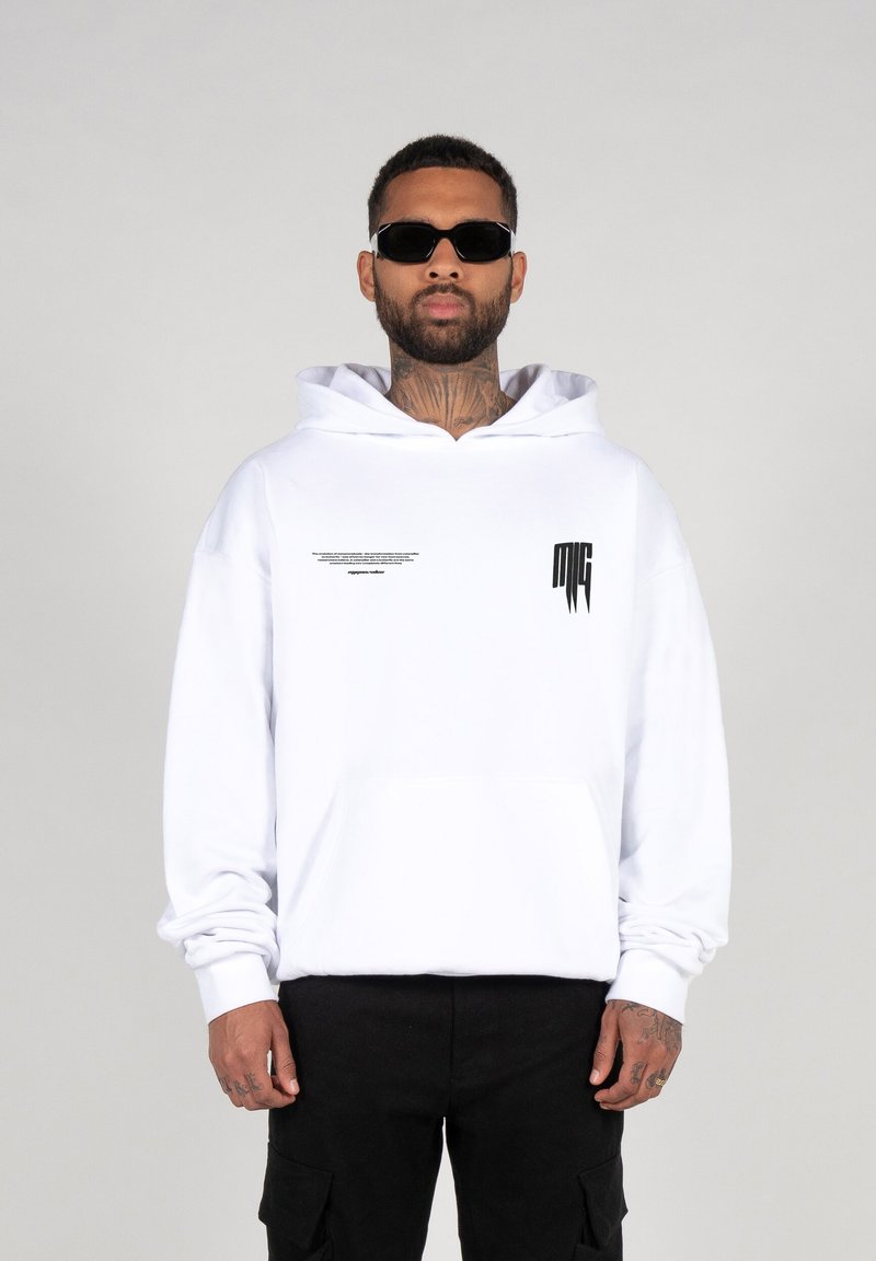 White cotton hoodie with a front pocket, large hood, and black text details on the front. Worn with black cargo pants and sunglasses.
