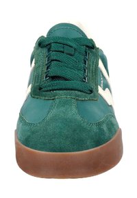 Zelené semišové a textilní tenisky mají šněrování vpředu, kontrastní bílé akcenty a hnědou gumovou podrážku. Zaoblený design špičky.