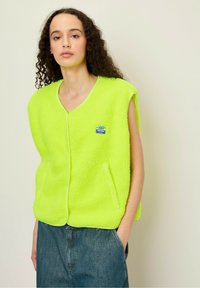 Neon yellow fleece vest with a V-neckline, sleeveless design, front pockets, and a small blue logo patch on the left side.