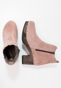 Vaaleanpunaiset mokkanahka ankle-boots, joissa on sivuvetoketju, pyöreä kärki ja paksu puinen korko. Koristeelliset tikkausompeleet reunassa lisäävät yksityiskohtia.