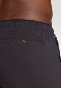 Μαύρα μαγιό σορτς με ελαστική μέση, φερμουάρ σε πλαϊνή τσέπη και κουμπωμένη πίσω τσέπη. Ομαλή υφή, ελαφρύ υλικό.