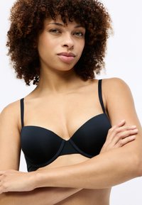 Zwarte padded bh met verstelbare bandjes, gladde textuur en naadloos ontwerp. Midden sluiting met een lichte U-vorm aan de voorkant.