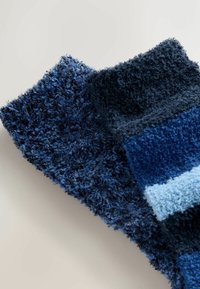 Minkštučiai kojinės įvairių mėlynų atspalvių, įskaitant tamsiai mėlyną ir šviesiai mėlyną. Minkšta tekstūra, neryškūs kraštai, ir skirtingi siūlų raštai.