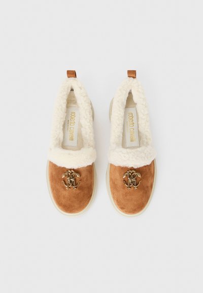 Brown suede slip-on shoes with a fluffy cream collar, featuring a gold logo accent and a textured rubber sole.