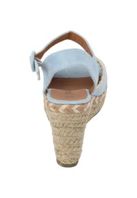 Sandalo con zeppa in suede azzurro chiaro, tacco in paglia intrecciata e punta arrotondata, dotato di un cinturino posteriore e chiusura con fibbia laterale.