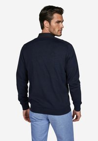 Marineblauer Strickpullover mit langen Ärmeln und einem gerippten Saum. Verfügt über ein klassisches Kragen-Design und eine glatte Textur, von hinten betrachtet.