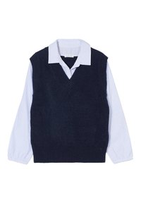 Marineblå ærmeløs sweater med V-hals, lagd oven på en hvid skjorte med blå striber. Har ribbede kanter og manchetter med knapdetaljer.