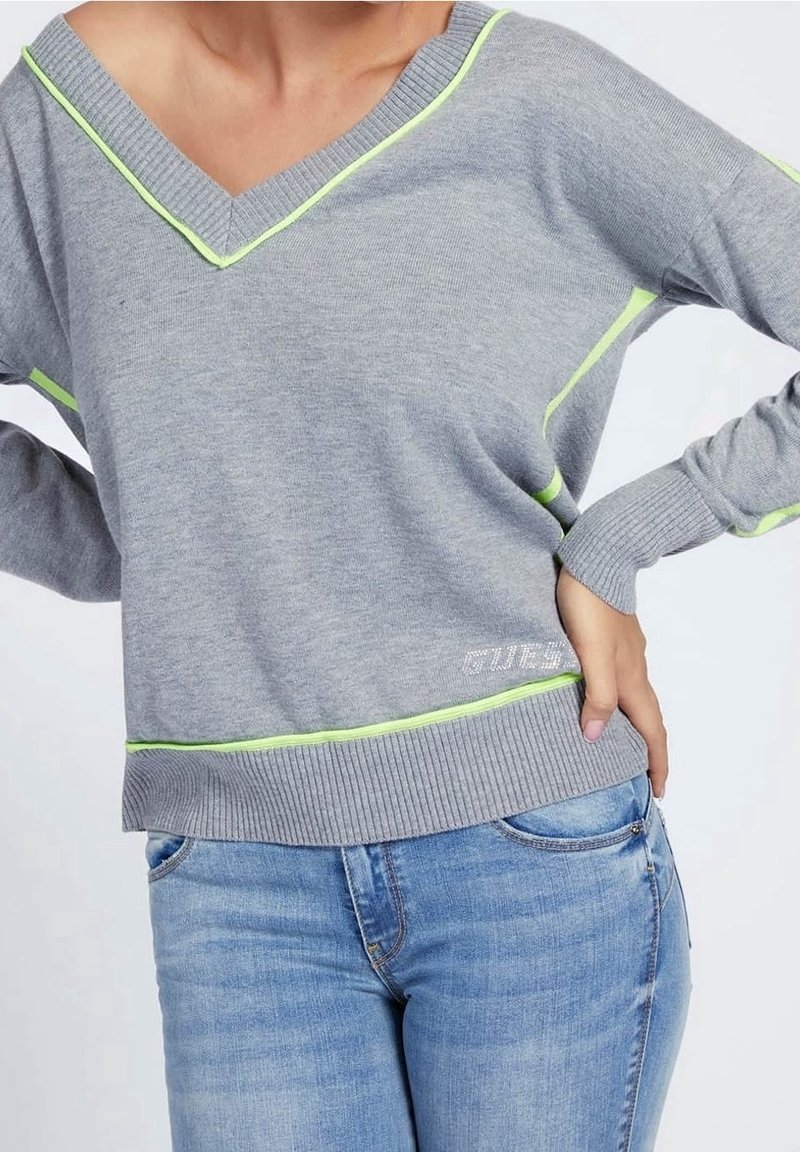 Pull gris à col en V, avec des accents vert néon le long de l'encolure et de l'ourlet. Texture en maille et poignets côtelés complètent le design.