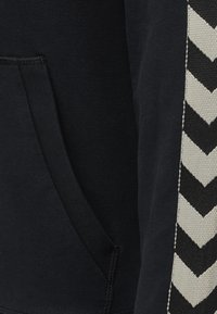 Felpa nera con cappuccio, dotata di tasca e una striscia a zigzag nera e crema lungo il lato, realizzata in morbido cotone.