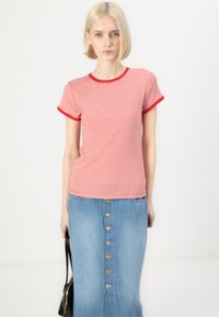 Rød og hvit stripete T-skjorte med kort erme og kontrasterende rød kant, sammen med et blått denimskjørt med frontknapper og slisse.