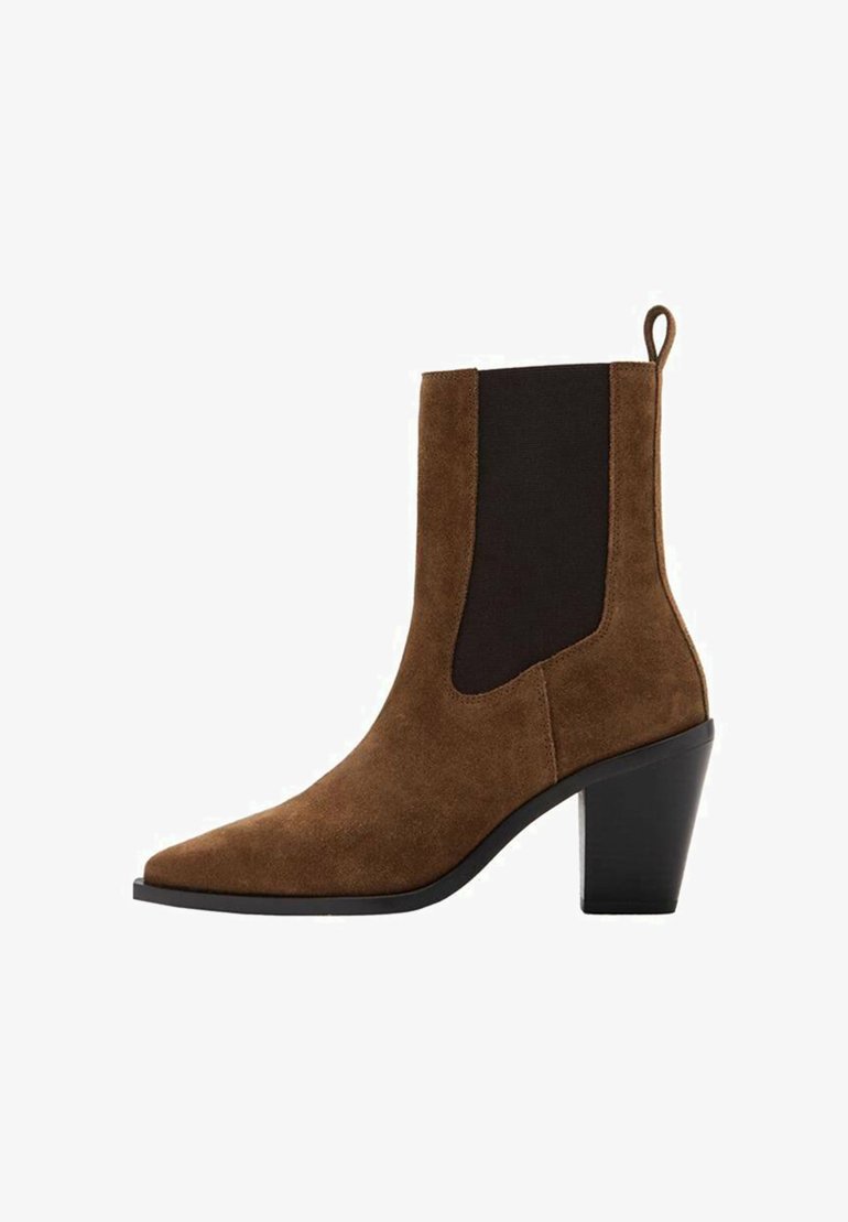 Cizme de gleznă din piele întoarsă maro, cu vârf ascuțit, panouri elastice laterale și toc gros. Dispune de un ornament sub formă de buclă în spate pentru a fi ușor de încălțat.