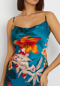 Satin-kjole i turkis med et blomstermønster i orange og pink blomster, justerbare spaghetti-stropper og en figursyet silhuet.