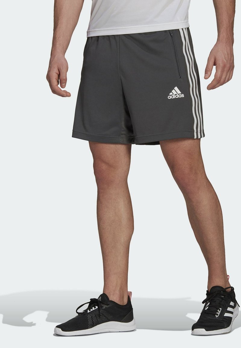 Pantalones cortos deportivos grises con rayas laterales blancas y un logo de adidas. Presentan una cintura elástica y un bolsillo lateral con cremallera.