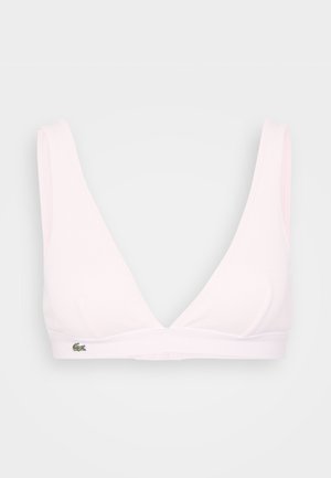 Valkoinen ribattu bralette, jossa on leveät hihnat ja V-mallinen kaula-aukko. Oikealla puolella pieni vihreä logo. Pehmeä, sileä pinta.