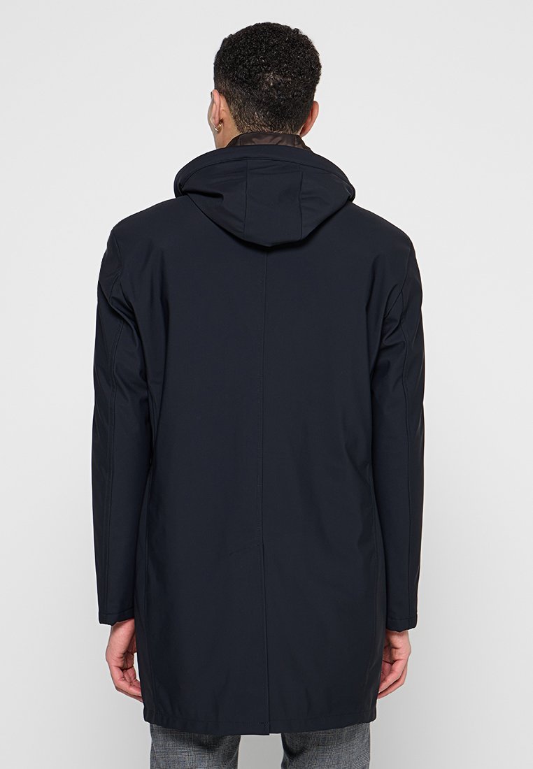 Marineblauer, kapuzengefertigter Mantel mit einem eleganten Design. Weicher, glatter Stoff zeichnet sich durch einen geraden Schnitt aus, mit einem Rückenventil und minimalem Zubehör.