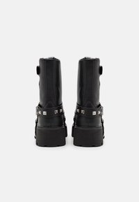 Bottes noires en cuir avec une finition texturée, doublure en fourrure, clous argentés et une semelle plateforme noire épaisse.