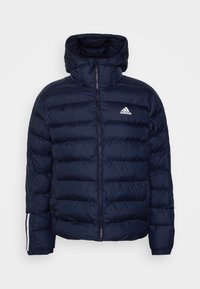 Marineblå puffjakke med høj krave, lynlås og hvid Adidas-logo. Har vandret syninger og elastiske manchetter med hvide striber.