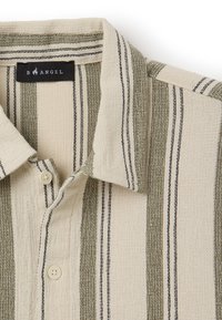 Camicia a maniche corte con colletto in beige con strisce verdi e blu navy. Il tessuto testurizzato e il dettaglio dei bottoni sono caratteristiche importanti.