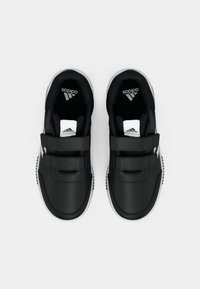 Crne Adidas tenisice s bijelim đonom i dvije Velcro trake, prikazane odozgo na bijeloj pozadini.