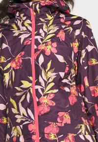 Bunda s květinovým vzorem na tmavě fialovém pozadí, jasně růžovými a žlutými květy a kontrastním růžovým zipem. Texturovaný design látky.