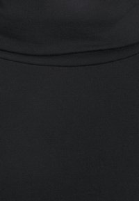 Gros plan d'un tissu noir avec un détail de couture pliée, montrant la texture et les coutures.