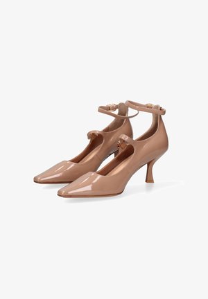 Talons en cuir verni nude avec orteils pointus, lanières de cheville, un design découpé et un talon stiletto modéré.