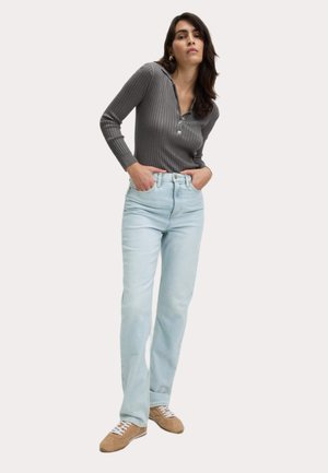 Grå ribbet langærmet top med knapplet, parret med lyseblå high-waisted jeans og beige sneakers med hvide snørebånd.