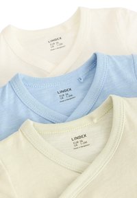 Trois t-shirts en coton doux de couleur crème, bleu clair et jaune pâle avec des encolures en V. Les étiquettes sont visibles sur chaque t-shirt.