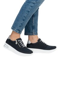 Baskets en daim bleu marine avec semelles blanches. Présentent des accents argentés, des lacets et un détail de zip sur le côté. Motif texturé sur la tige.