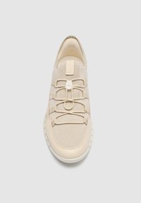 Baskets beiges en tissu mesh, lacets élastiques sans nouer, et semelle blanche vues de dessus sur un fond uni.