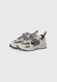 Laufschuhe aus leichtem beigen und braunem Mesh mit einem schwarzen Swoosh und reflektierenden Akzenten. Verfügt über eine strukturierte Sohle und Zuglaschen für einfachen An- und Ausziehen.
