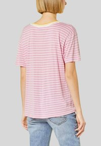 Camiseta de manga corta a rayas rosa y blanca con cuello redondo, que presenta un ribete amarillo en el collar. La tela parece suave y ligera.