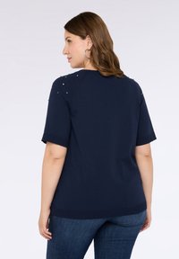 Top blu navy a maniche corte con scollo rotondo, caratterizzato da perline decorative multicolori sulle spalle; tessuto a maglia testurizzato.