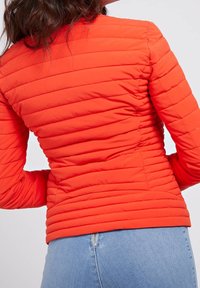 Giacca imbottita rossa con design aderente e cuciture orizzontali. Presenta uno scollo arrotondato e maniche lunghe.