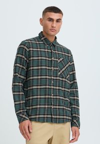 Grøn- og sortternet flannel skjorte med lange ærmer, knaplukning foran, enkelt brystlomme og en afslappet pasform.
